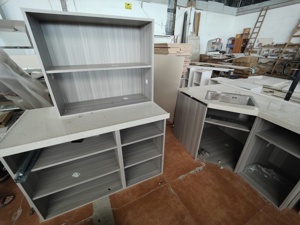 Full layout pre-assembly of sink cabinet, base cabinets and tall unit in factory workshop 